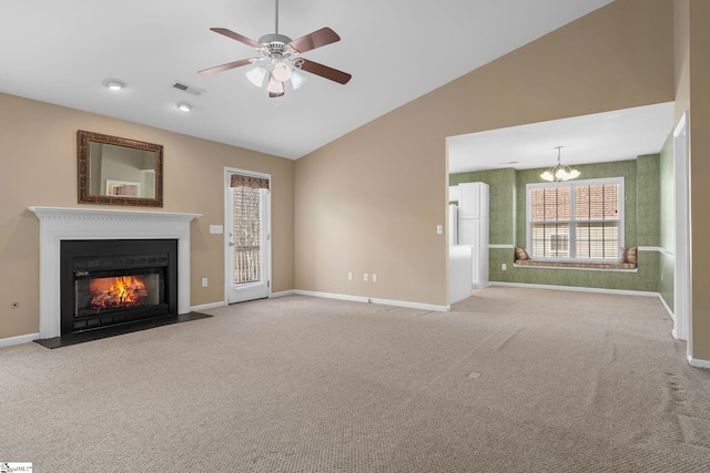 unfurnished living room with ceiling fan with notable chandelier, vaulted ceiling, and light carpet