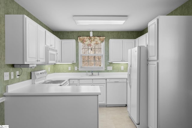 kitchen featuring white cabinetry, sink, white appliances, and kitchen peninsula