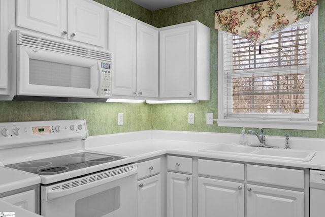 kitchen with white appliances, a healthy amount of sunlight, sink, and white cabinets