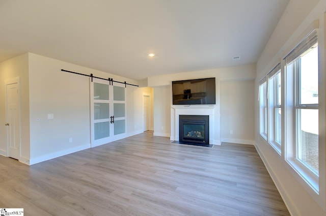 unfurnished living room featuring a barn door and light hardwood / wood-style flooring