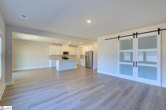 unfurnished living room featuring light hardwood / wood-style floors and a barn door