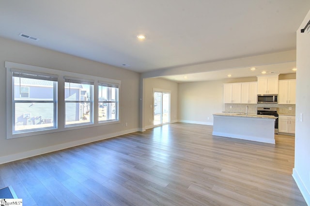 unfurnished living room featuring sink and light hardwood / wood-style flooring