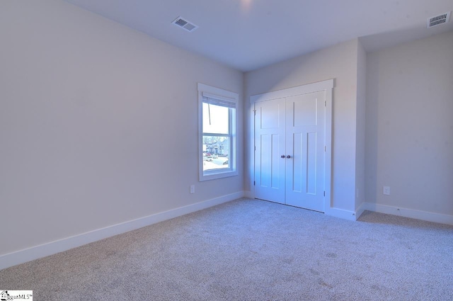 unfurnished bedroom with light colored carpet and a closet