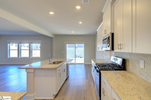 kitchen featuring sink, white cabinetry, light stone counters, a center island with sink, and appliances with stainless steel finishes