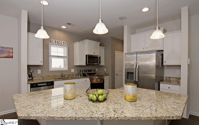 kitchen with light stone counters, a center island, appliances with stainless steel finishes, pendant lighting, and white cabinets