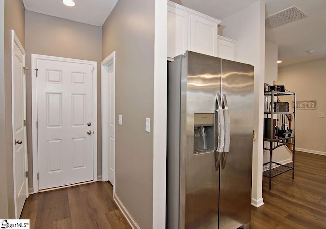 kitchen with dark wood-type flooring, stainless steel fridge, and white cabinets