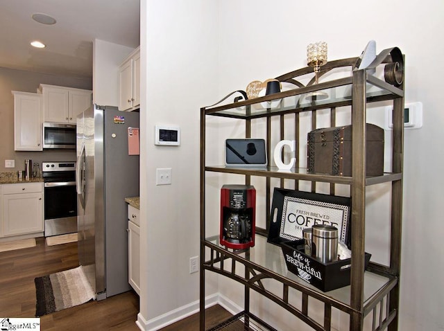 interior space with white cabinetry, stainless steel appliances, light stone countertops, and dark wood-type flooring