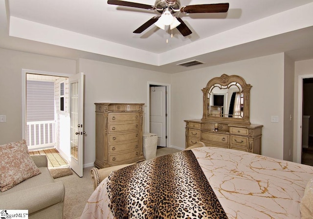 bedroom with ceiling fan, light colored carpet, and a raised ceiling