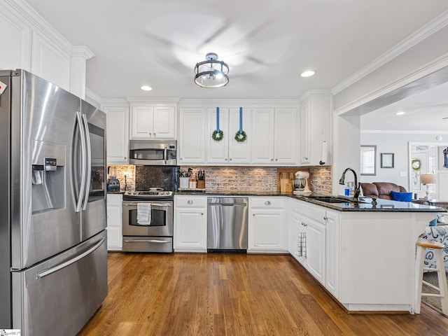 kitchen featuring appliances with stainless steel finishes, sink, white cabinets, decorative backsplash, and kitchen peninsula