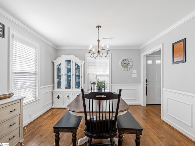 dining space with wood-type flooring, crown molding, and an inviting chandelier