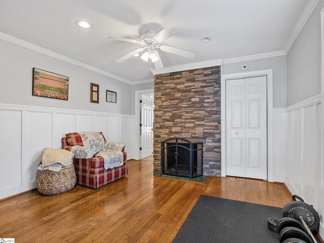 living room with crown molding, ceiling fan, a fireplace, and hardwood / wood-style floors