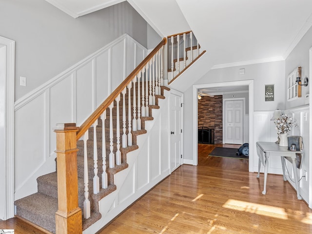 staircase featuring hardwood / wood-style flooring, crown molding, and a fireplace