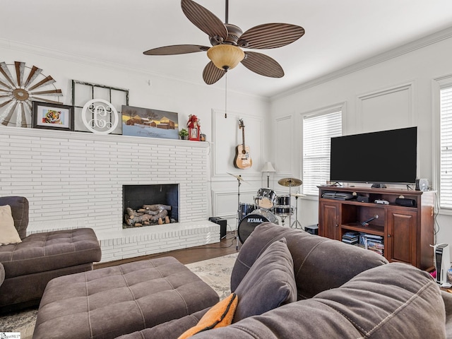 living room with a fireplace, wood-type flooring, ornamental molding, and ceiling fan