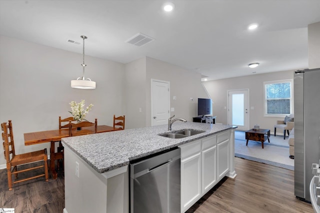 kitchen with appliances with stainless steel finishes, pendant lighting, white cabinetry, an island with sink, and sink