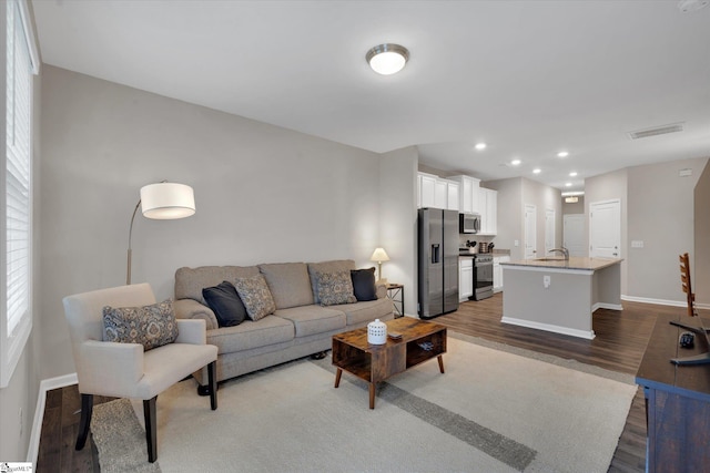 living room with plenty of natural light, dark hardwood / wood-style flooring, and sink