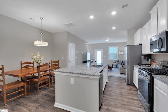 kitchen featuring stainless steel appliances, white cabinetry, sink, and a center island with sink