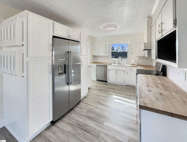 kitchen featuring sink, butcher block countertops, stainless steel appliances, light hardwood / wood-style floors, and white cabinets