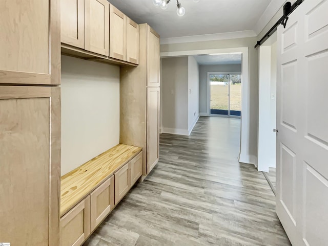 mudroom featuring ornamental molding, a barn door, and light hardwood / wood-style floors