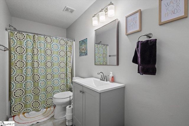 bathroom with vanity, toilet, and a textured ceiling