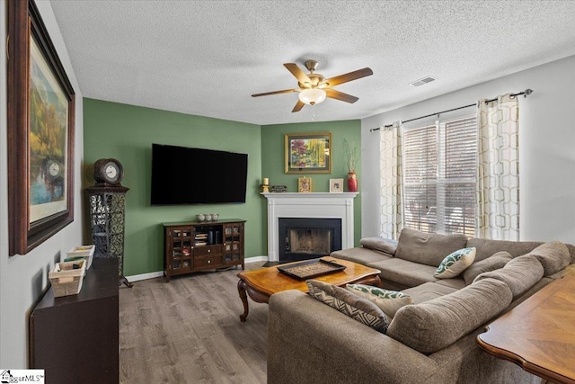 living room featuring hardwood / wood-style flooring, a textured ceiling, and ceiling fan