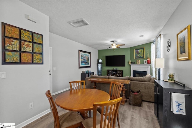 dining area featuring ceiling fan, hardwood / wood-style flooring, and a textured ceiling