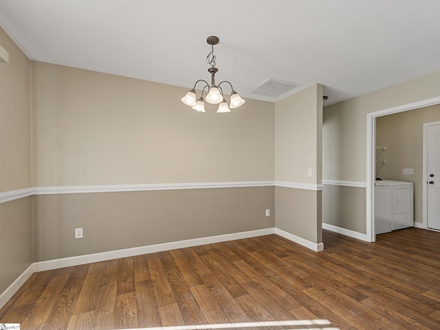 unfurnished room featuring dark hardwood / wood-style flooring, independent washer and dryer, and a chandelier