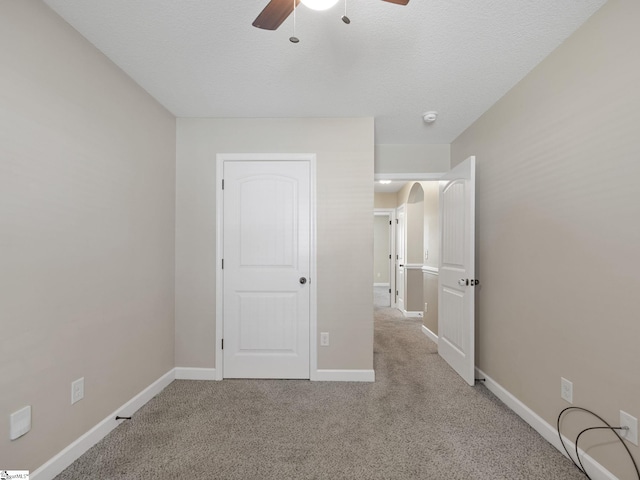 unfurnished bedroom featuring ceiling fan, light colored carpet, and a textured ceiling