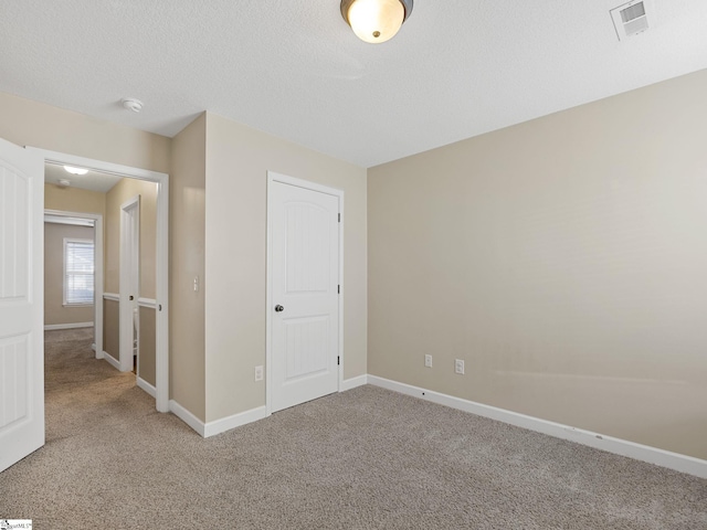 unfurnished bedroom featuring light carpet and a textured ceiling