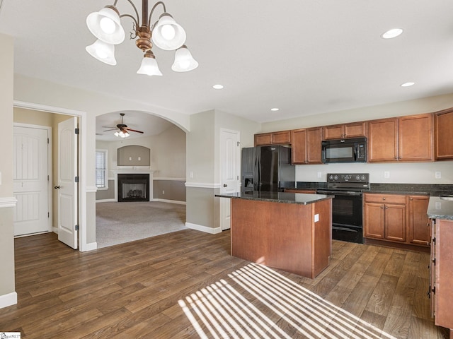 kitchen with a kitchen island, dark stone countertops, dark hardwood / wood-style flooring, ceiling fan, and black appliances