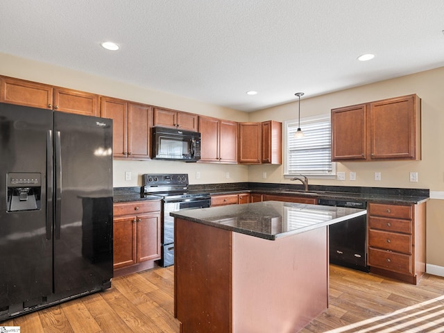 kitchen with a kitchen island, pendant lighting, light hardwood / wood-style floors, and black appliances