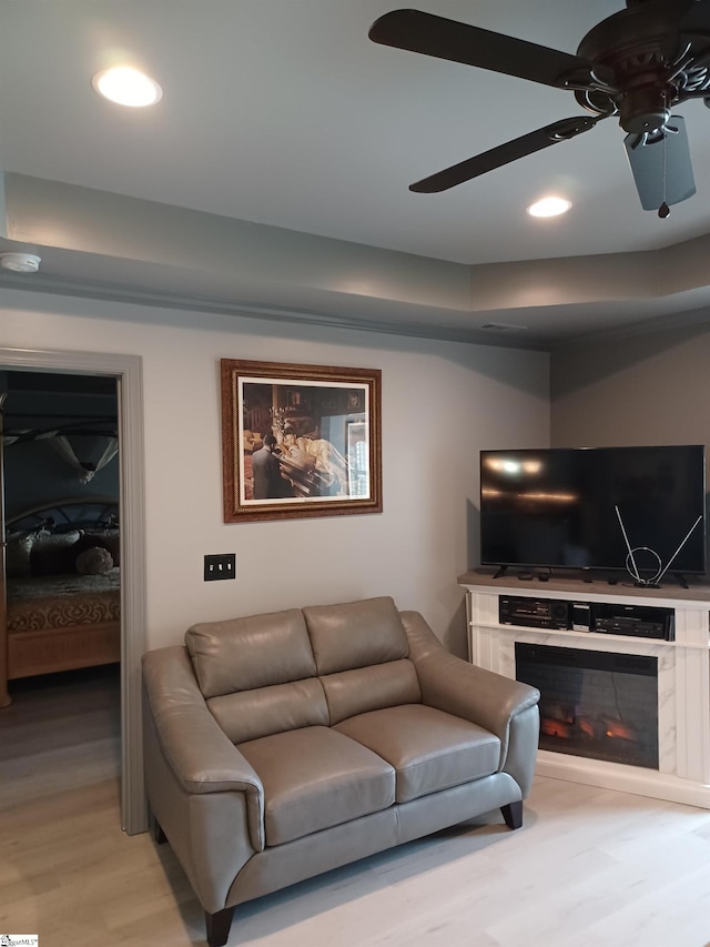 living room with ceiling fan, a fireplace, and light wood-type flooring