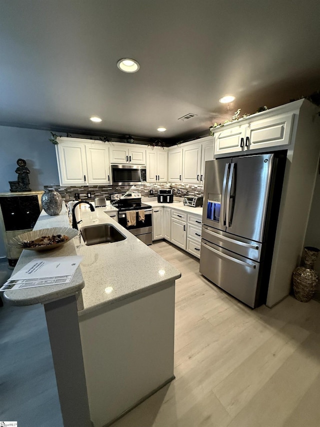 kitchen featuring sink, stainless steel appliances, kitchen peninsula, and white cabinets