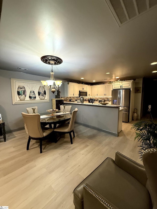 dining area with an inviting chandelier and light hardwood / wood-style floors