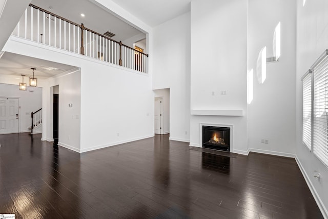 unfurnished living room with a high ceiling and dark hardwood / wood-style flooring