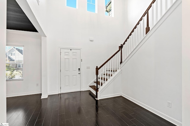 foyer entrance with dark wood-type flooring and a high ceiling