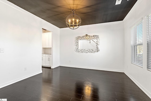 spare room with dark wood-type flooring and an inviting chandelier