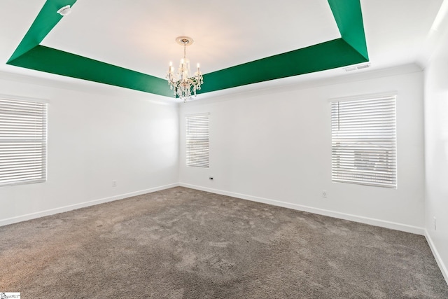 unfurnished room featuring carpet flooring, a tray ceiling, and a chandelier