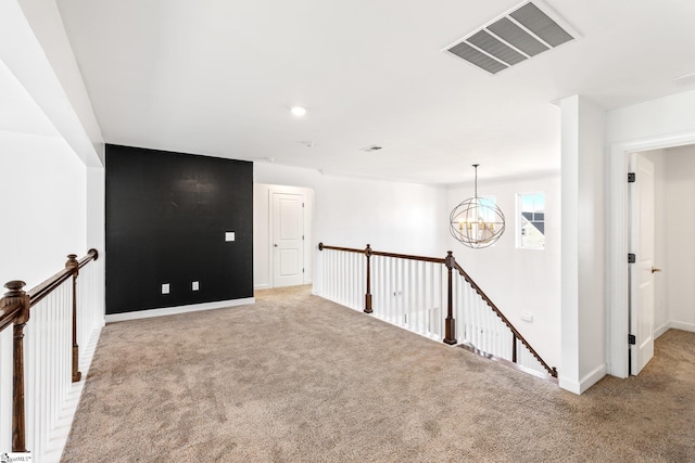 carpeted empty room with a notable chandelier