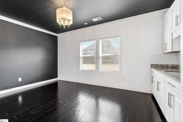 unfurnished dining area with crown molding, dark hardwood / wood-style floors, and a chandelier