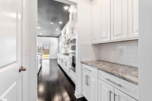 kitchen with dark wood-type flooring, tasteful backsplash, light stone countertops, stainless steel gas cooktop, and white cabinets