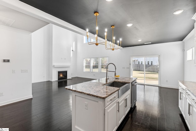 kitchen with white cabinetry, decorative light fixtures, sink, and light stone counters