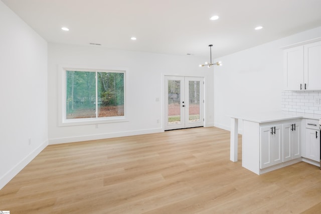 interior space featuring an inviting chandelier, light wood-type flooring, and french doors