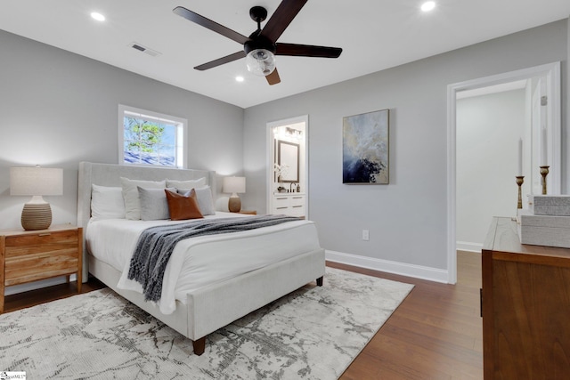 bedroom featuring hardwood / wood-style flooring, ensuite bathroom, and ceiling fan