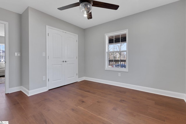 unfurnished bedroom with dark wood-type flooring, ceiling fan, and a closet