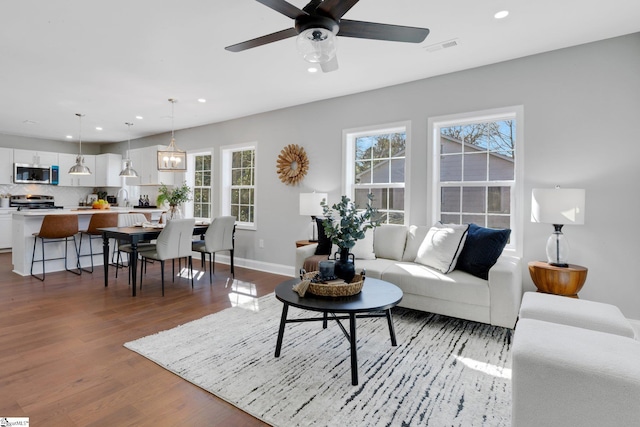 living room with dark hardwood / wood-style flooring, sink, and ceiling fan