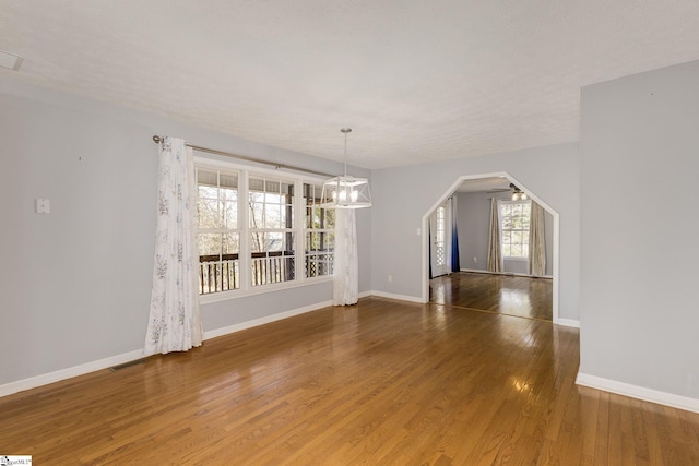 unfurnished dining area featuring ceiling fan with notable chandelier and dark hardwood / wood-style flooring