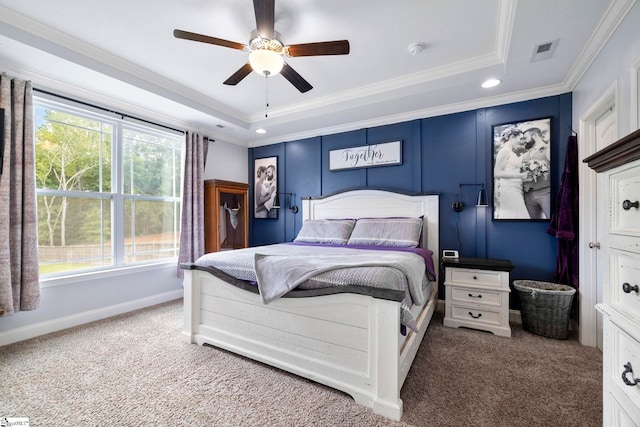 carpeted bedroom with a tray ceiling, ornamental molding, and ceiling fan