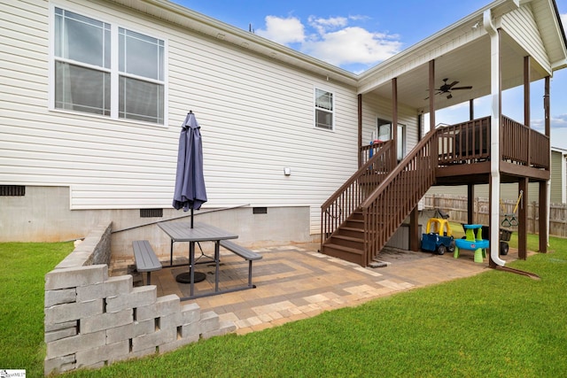 rear view of property featuring a wooden deck, ceiling fan, a patio area, and a lawn