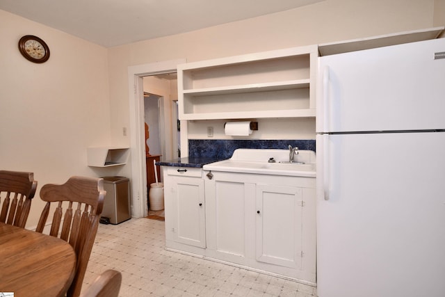 kitchen with white cabinetry, sink, and white refrigerator