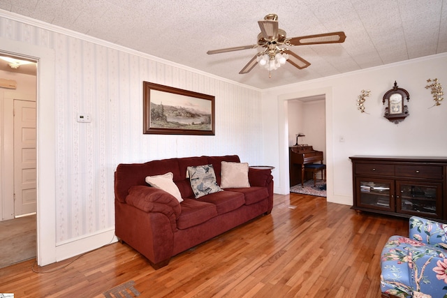 living room with hardwood / wood-style flooring, ceiling fan, ornamental molding, and a textured ceiling